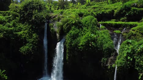 Aerial-view-of-flowing-and-falling-Kembar-Arum-Waterfall-in-tropical-landscape-in-Indonesia,Asia