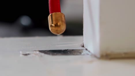 a specialized high-voltage probe generates a fine electrical arc that scans a sealed surface, pinpointing invisible pinholes or flaws as part of an industrial quality control inspection