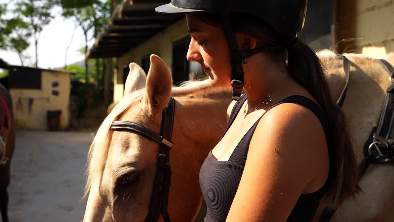 Female horse rider pauses at the stable door awaiting instruction to head to the arena on a sunny morning