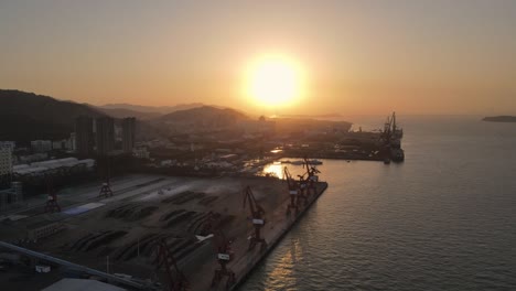 the aerial video of sunset shows the crane and container of the wharf from the top view angle