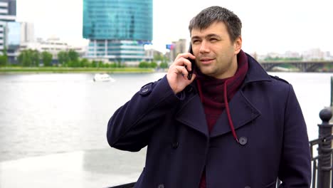 a man is talking on a mobile phone against the backdrop of a cityscape.