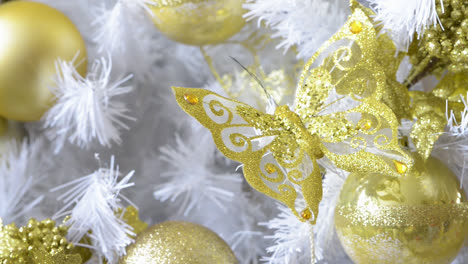 detalle de un hermoso árbol de navidad blanco adornado con mariposas doradas y bolas