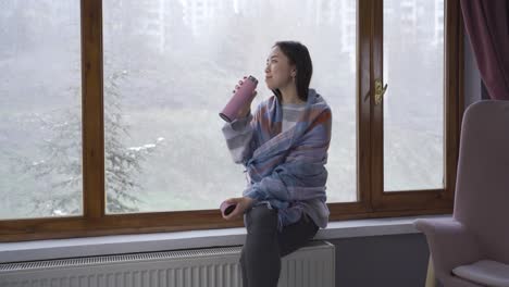 asian young woman looking out the window at home.