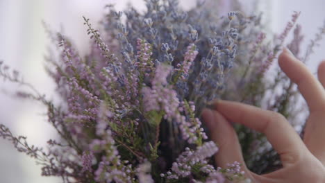 female hand puts a bouquet of lavender on a wooden table