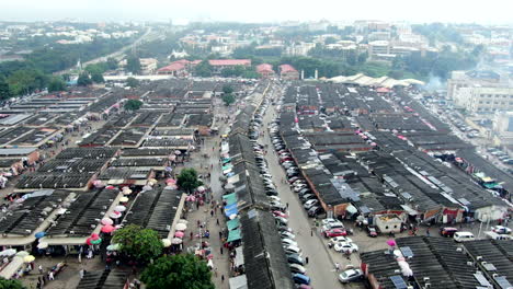 Wuse-Market-in-Abuja,-Nigeria-store-stalls-and-people-shopping---descending-aerial-view