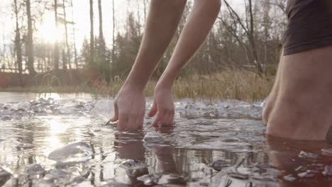 an ice bather walks into a lake and starts clearing surface ice away