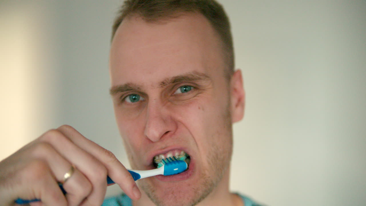 Close up of man's face brushing his teeth with a toothbrush in slow motion