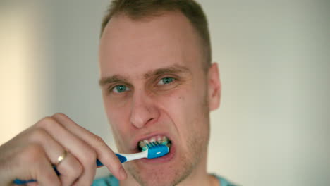 close up of man's face brushing his teeth with a toothbrush in slow motion