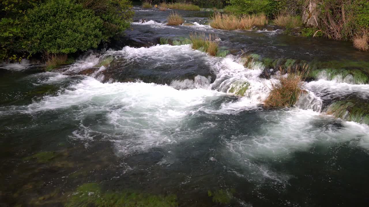 Acqua che scorre da un livello all'altro con piante verdi e marrone chiaro intervallate nel Parco Nazionale di Krka in Croazia.
