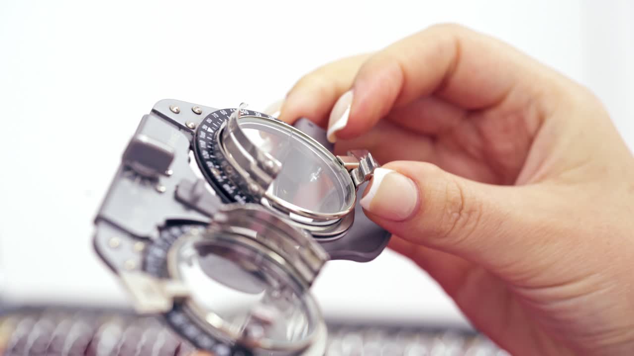 Woman's hand taking lens for putting it into testing glasses. Image of an optometry set. Lens set for the selection of points. Close-up.