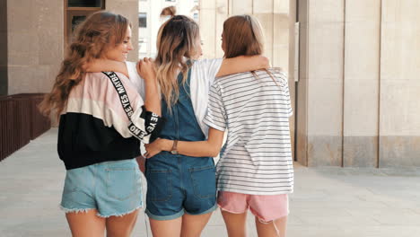 three women friends walking together in a city