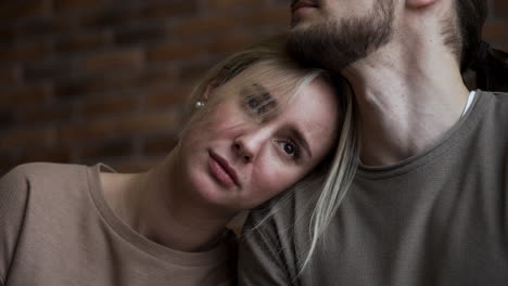 una pareja joven con caras tristes en casa.