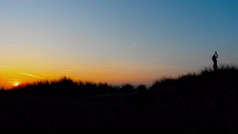 Side-view-of-woman-practising-yoga-in-nature-while-sunset