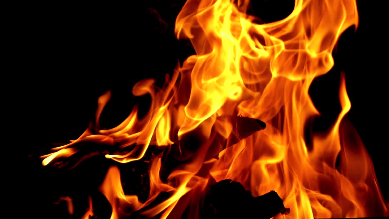 Slow motion of fire at bonfire in the dark, closeup. Bonfire sparks and hot embers at night.
