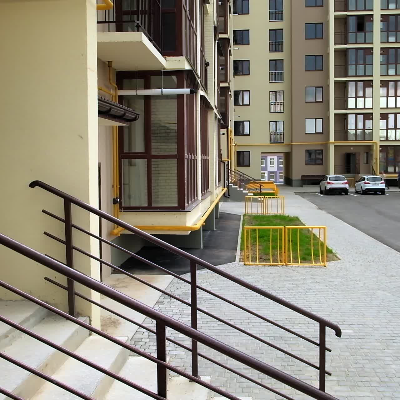 Newly built residential multistoried building exterior. Private cars parked at the parking lots