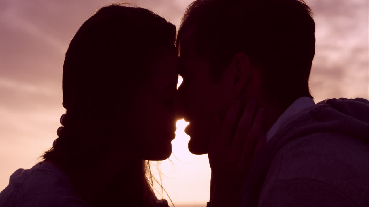 행복한 사랑하는 커플이 해가 지면에 키스하고 감정적 인 친밀감을 보여주고 만지며 포옹하고  ⁇ 안고 있습니다.