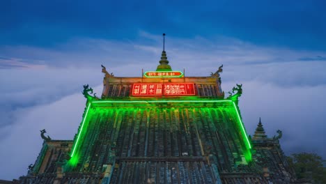 ornate temple roof illuminated with green neon lights against a twilight sky