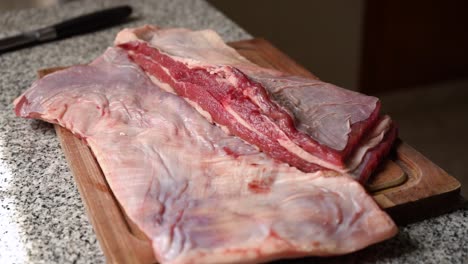 Woman-picking-up-a-cutting-board-with-freshly-cut-meat