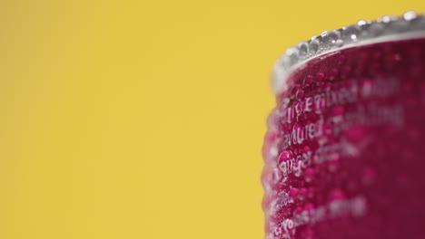 acercamiento de gotas de condensación en una lata giratoria de cerveza fría o refresco para llevar contra un fondo amarillo con espacio para copiar 4