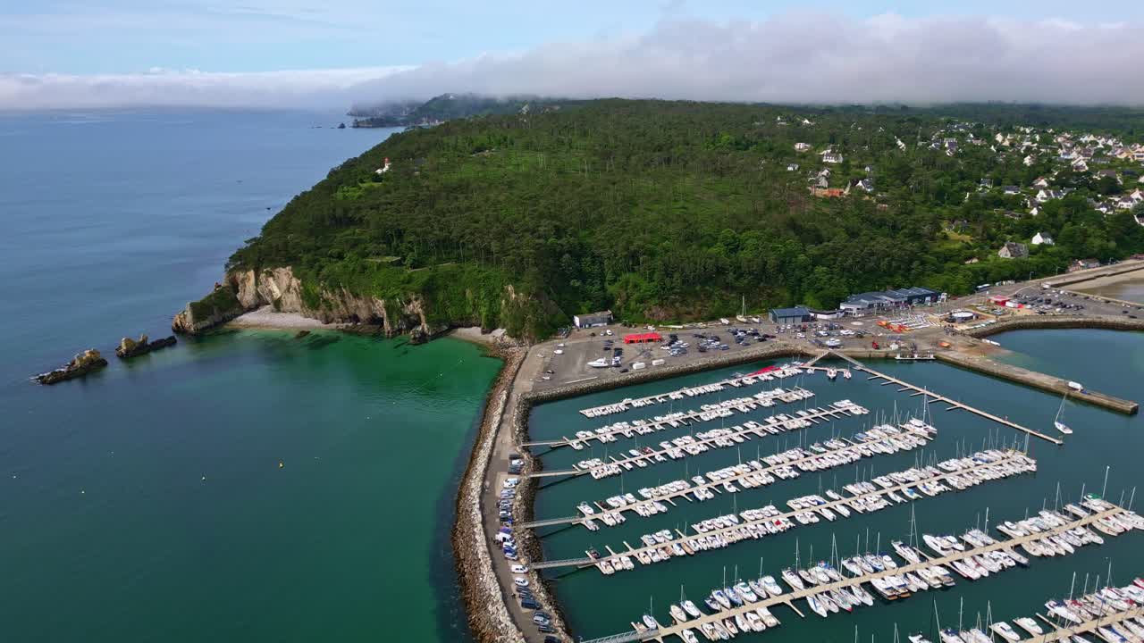 Aerial of Morgat marina and boats docked in calm bay, Crozon Peninsula, Brittany, establishing pullback overview
