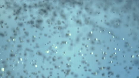 multitud de cristales de azúcar cayendo al agua, filmados en cámara lenta, la luz ilumina parte de los cristales.