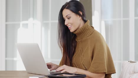 mujer atractiva sentada escribiendo en una computadora portátil