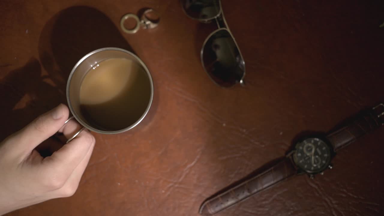 A Cup Of Brown Coffee, Watch, Sunglasses, And A Pair Of Rings On The Table - Flatlay - close up