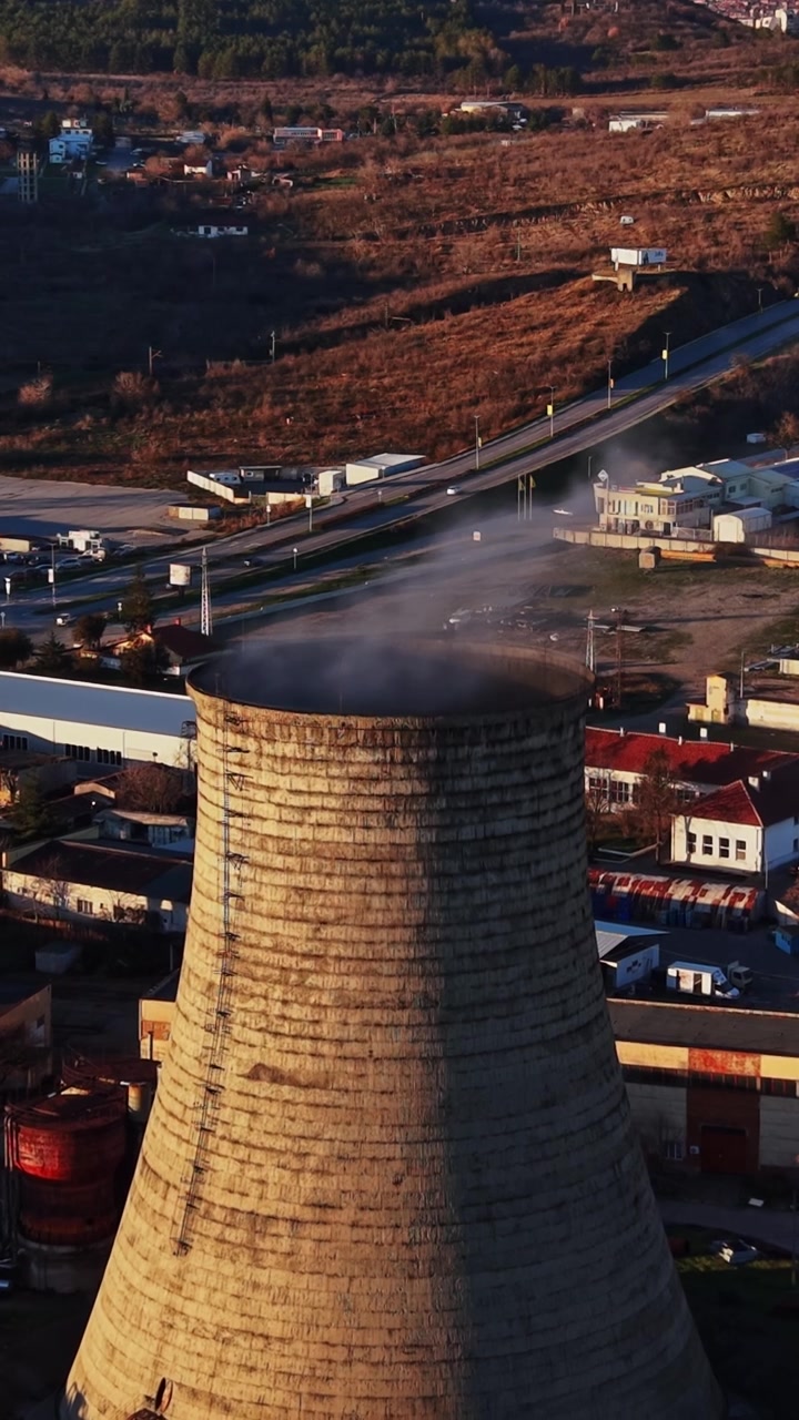 La torre di raffreddamento rilascia vapore sopra un'area industriale e il paesaggio circostante