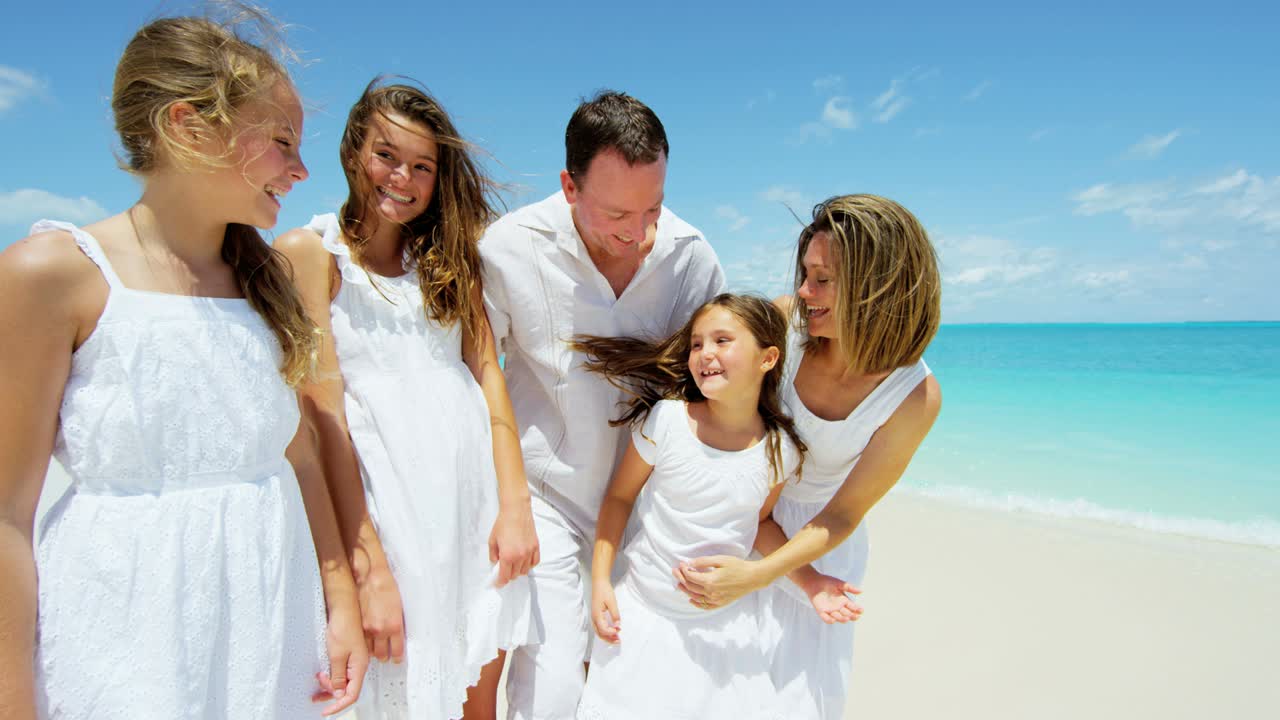 사랑스러운 백인 부모와 여자 아이들이 해변에