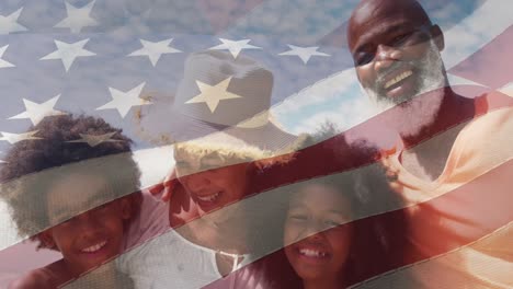 animation of flag of usa over happy senior biracial couple with grandchildren on beach