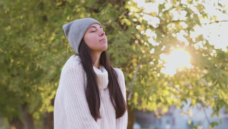 mujer relajada respirando aire fresco de pie en el parque en otoño