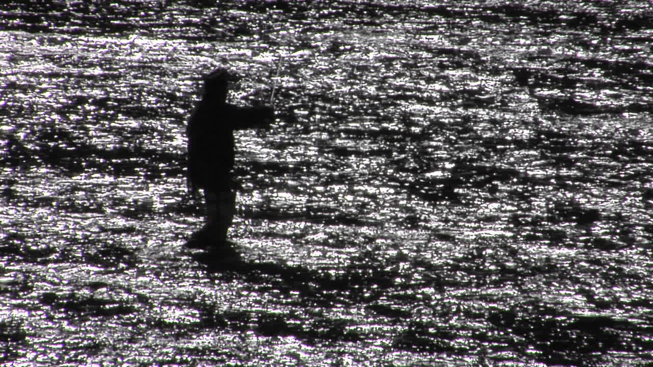 넓고 얕은 강에서 플라이 낚시를 하는 남자