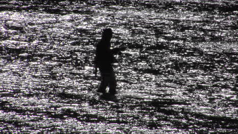 un hombre pesca con mosca en un amplio río poco profundo