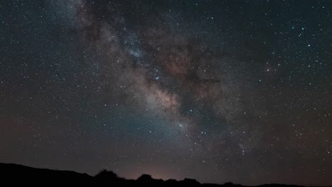rastreando la vía láctea en colores brillantes mientras cruza el cielo sobre el horizonte del desierto - lapso de tiempo