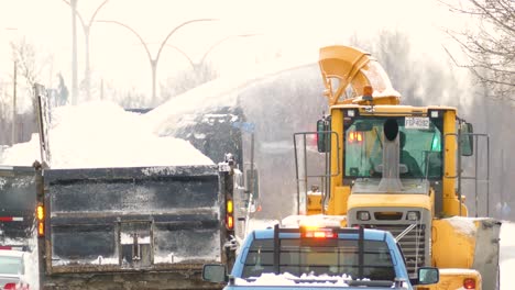 snow collector throwing snow onto a collection truck