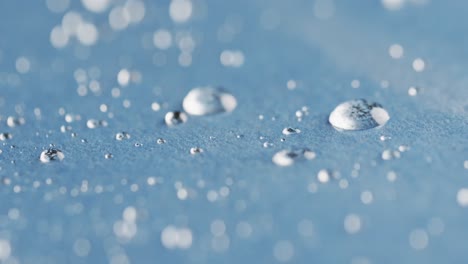 micro video of close up of water drops with copy space on blue background