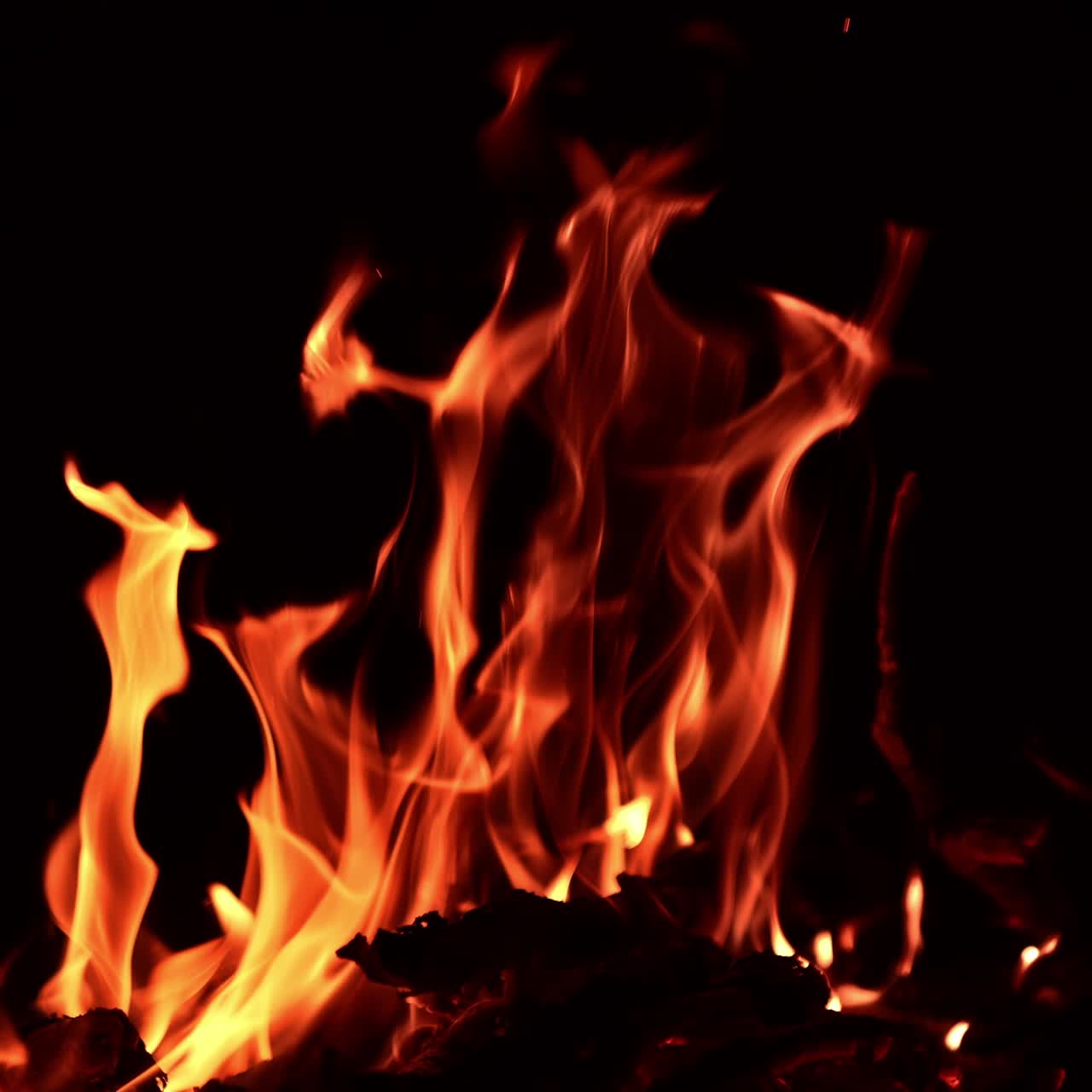 Tronchi di legno che bruciano nel falò di notte. Un bastoncino si rompe e si alzano molte scintille