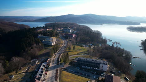 Backwards-aerial-view-of-buildings-at-the-lake-in-the-park-of-Polanczyk