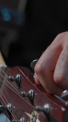 close-up of a hand tuning an acoustic guitar