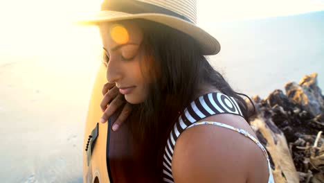 chica india americana chillando en la playa con la guitarra