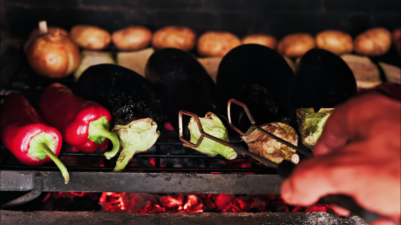 Close up of eggplants, potatoes, onions, peppers and courgettes cooking on a grill