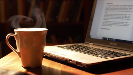 a cozy scene of morning coffee steaming next to a laptop on a wooden table, perfectly capturing a serene atmosphere for work and relaxation