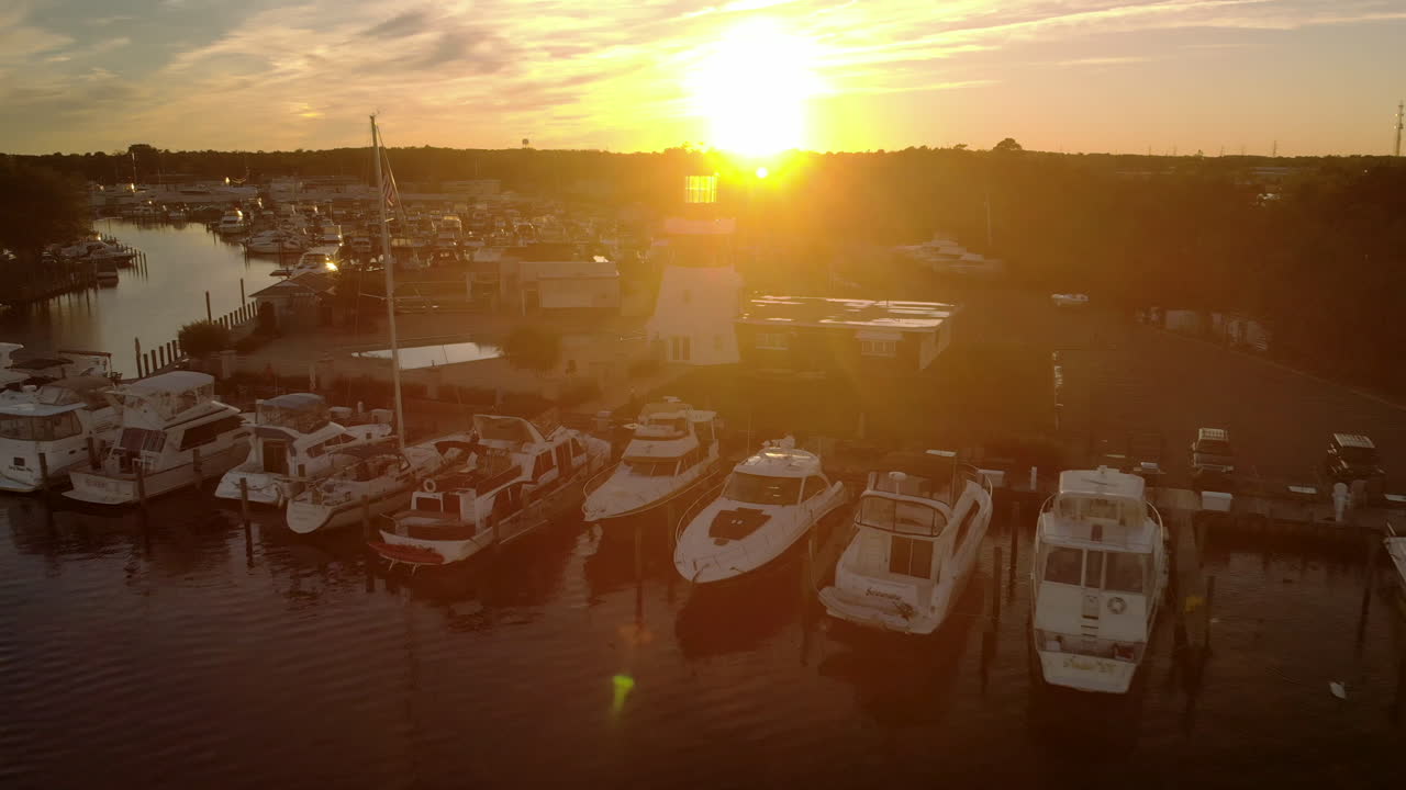 잔잔한 강에 있는 아름다운 작은 마을 항구에 있는 소박한 등대 뒤에 있는 일몰의 공중 철수