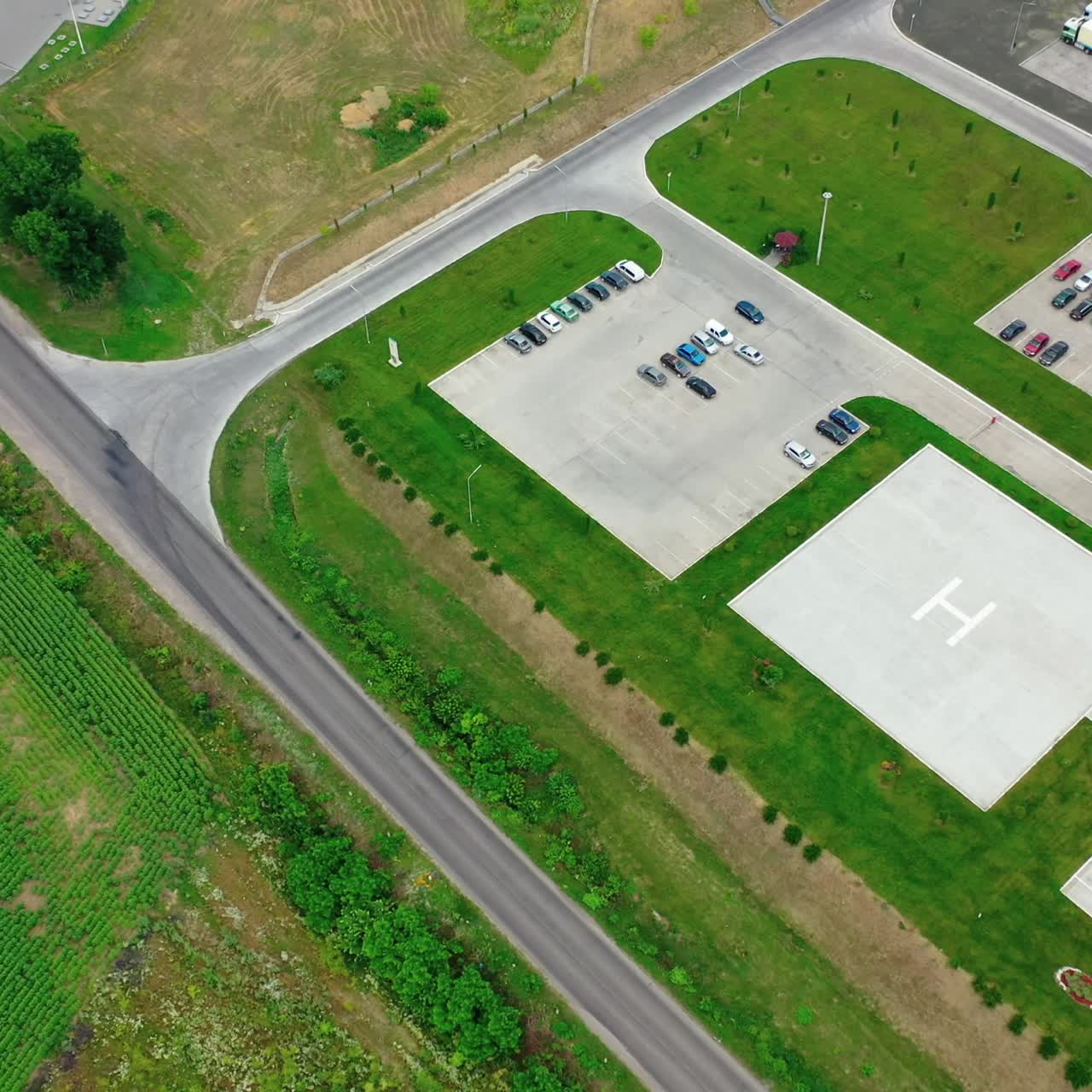 Car places on green field near the road.The entrance into the modern industrial plant with cars on parking. Aerial orbital view