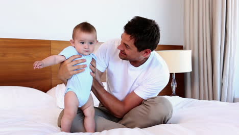 happy father sitting with baby son on bed