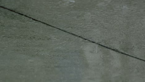 gotas de agua de lluvia de verano o otoño en cámara lenta caen sobre el asfalto en la ciudad convirtiéndose en un gran charco, inundando la calle