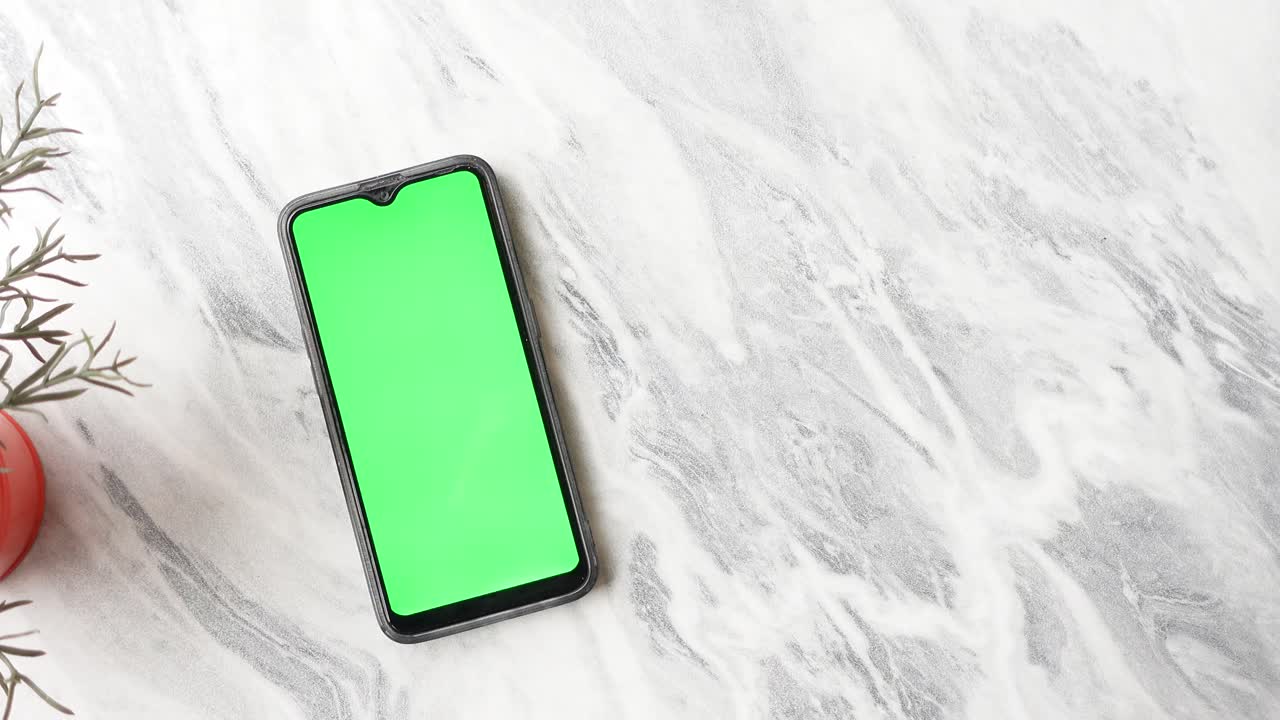 Smartphone con schermo verde su tavolo di marmo
