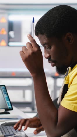 vertical video african american technician evaluates renewable energy metrics at pc station