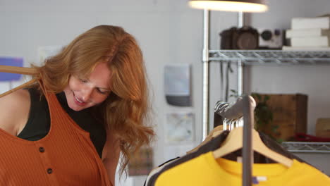 female clothes designer checking clothing samples on rail in fashion studio