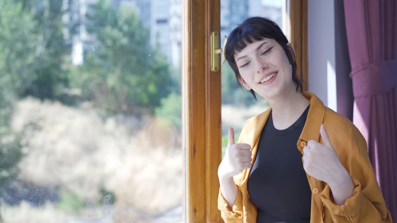 젊은 여성이 카메라에 축하 메시지를 보내며 박수를 치고 있습니다.